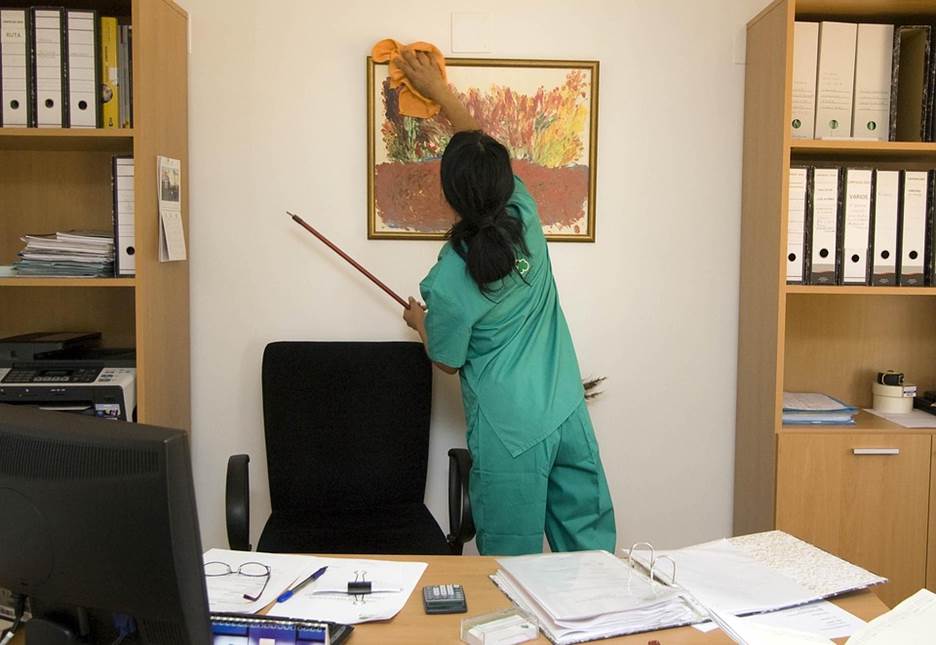 A janitor lady can be seen cleaning an office