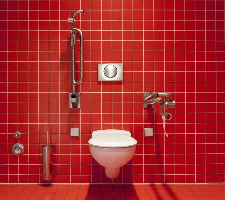A bathroom with red tile and white grout
