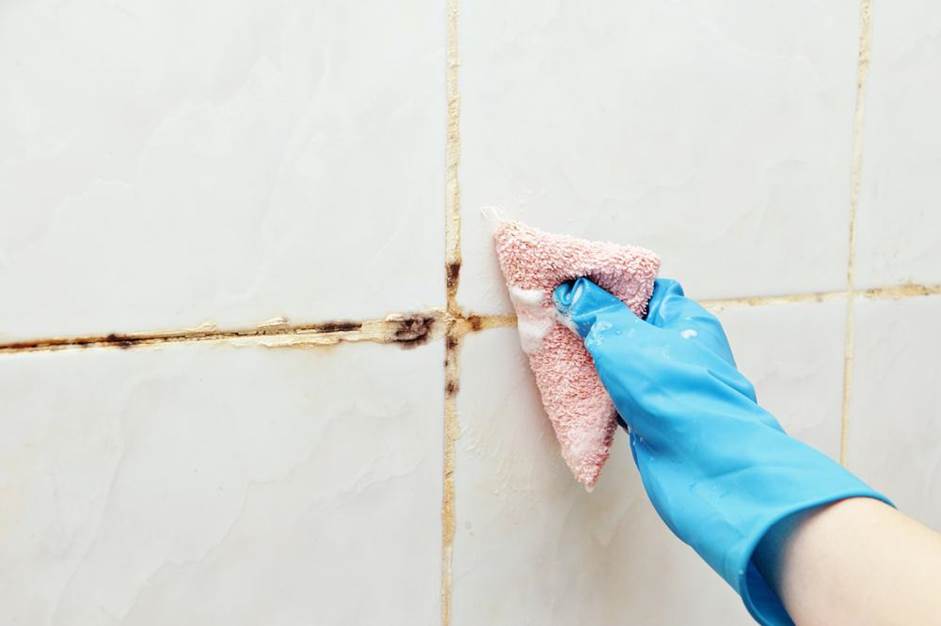 A woman cleaning the tiles and grout