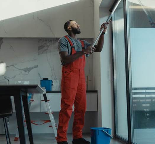 A professional cleaning the windows of the office