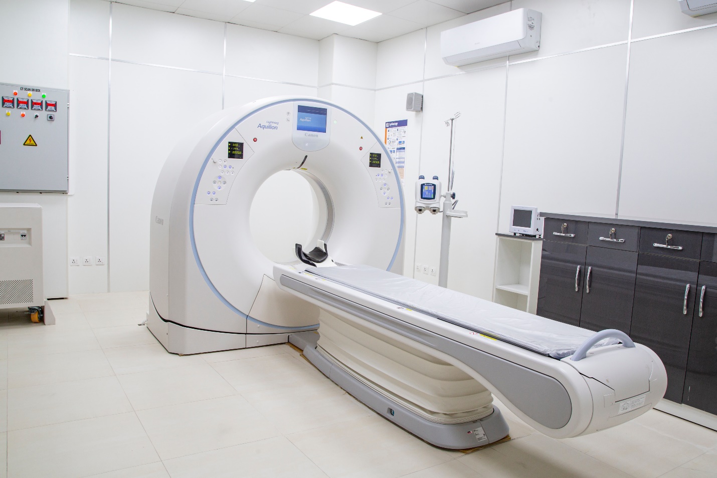 An MRI machine in a hospital facility flanked by a black storage unit and white walls and floor