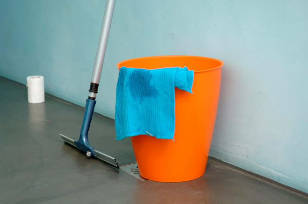 a wiper next to an orange bucket with blue colored cloth in it