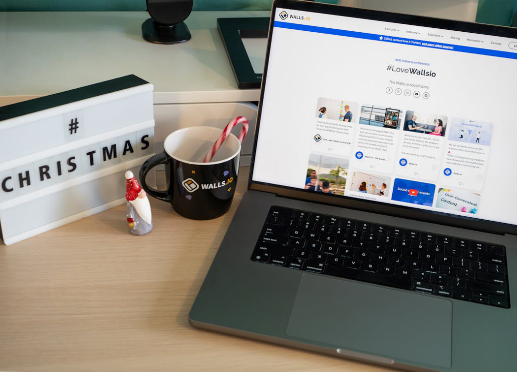 A clean and organized office desk with a laptop, festive mug holding candy canes, and a lightbox displaying “#Christmas,” suggesting a holiday-ready workspace.