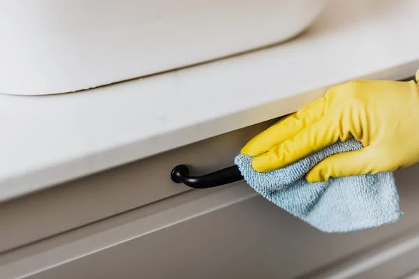 Janitorial staff cleaning office door handles with a rag, ensuring consistency and high hygiene standards.