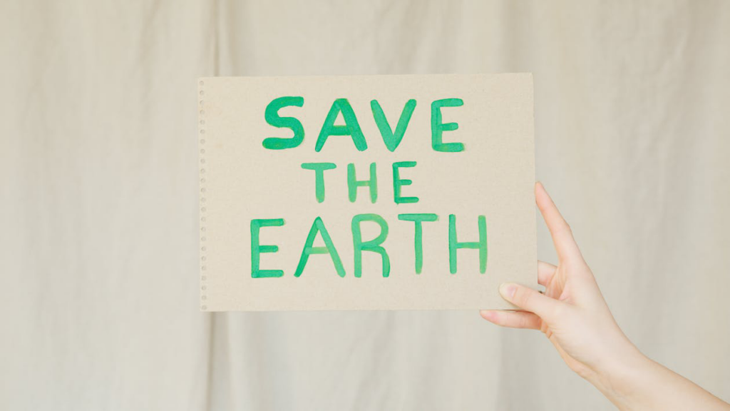 An image of a person holding a “Save the Earth” poster