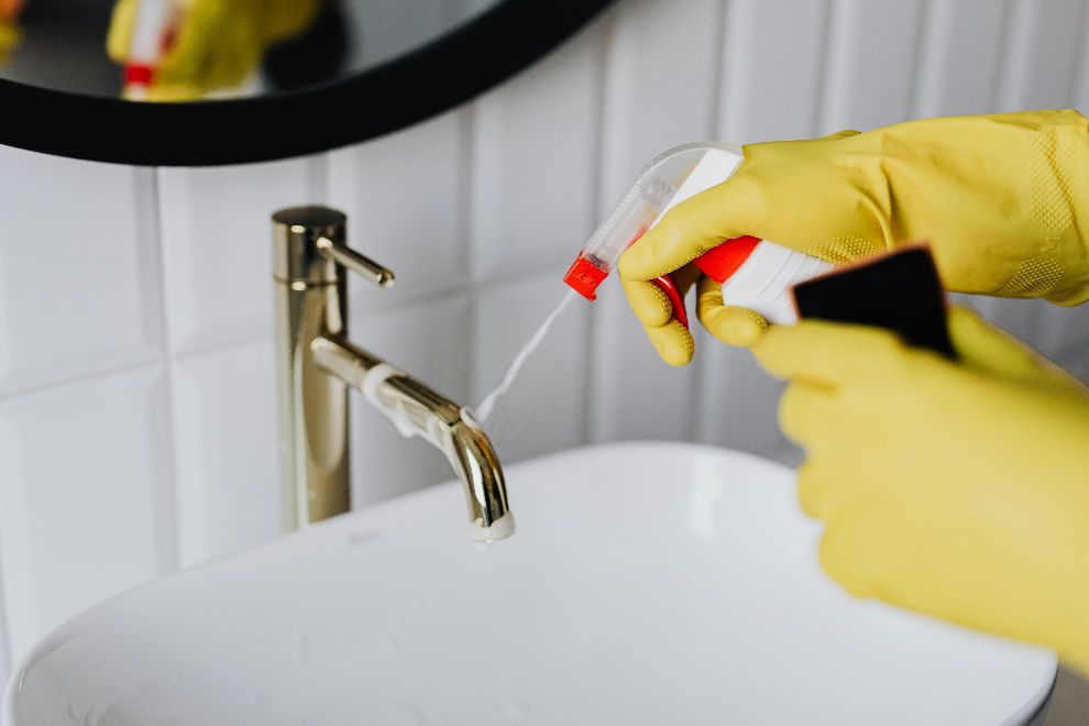 Person wearing gloves cleaning a tap