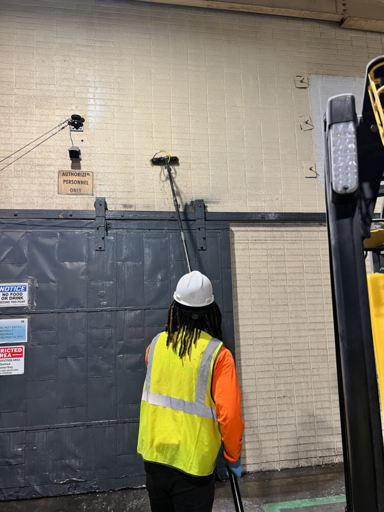 janitor doing high-dusting on a tiled wall