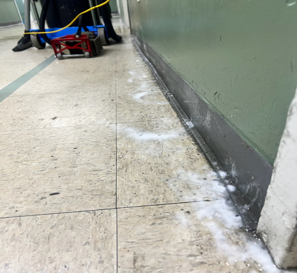 Close-up of the floor corner covered in foam during a cleaning process