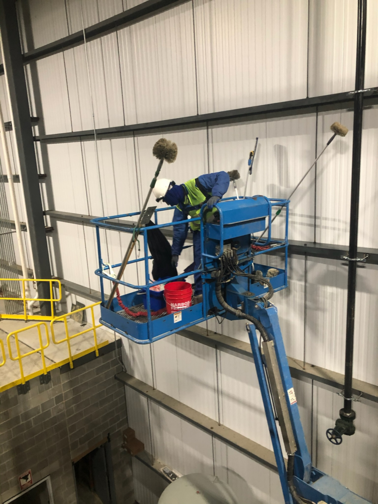 a janitor on a crane doing high-dusting in a warehouse