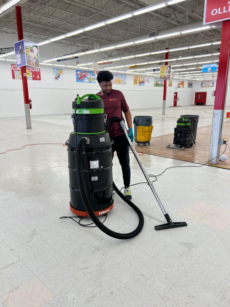 janitorial member using a high-pressure vacuum to clean the floor