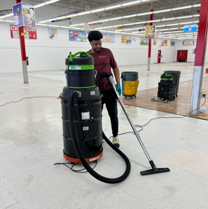 Worker in a red shirt standing with large cleaning equipment used for deep tile cleaning.
