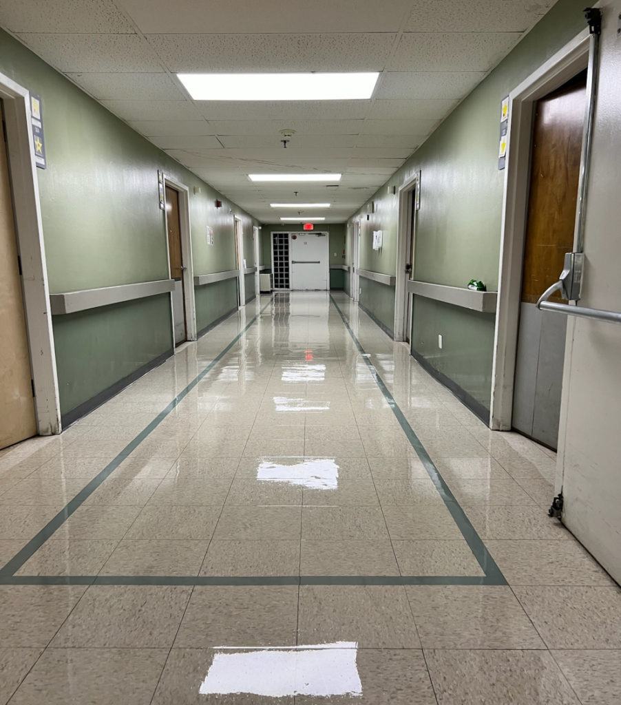 A spotless school corridor with shiny floors, bright lighting, and clean walls.