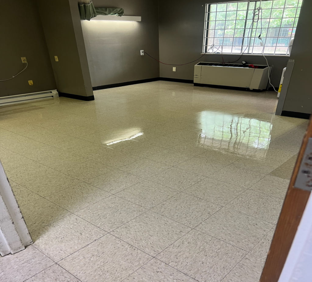 A clean tiled floor in a room with grey walls and one window letting in natural light.