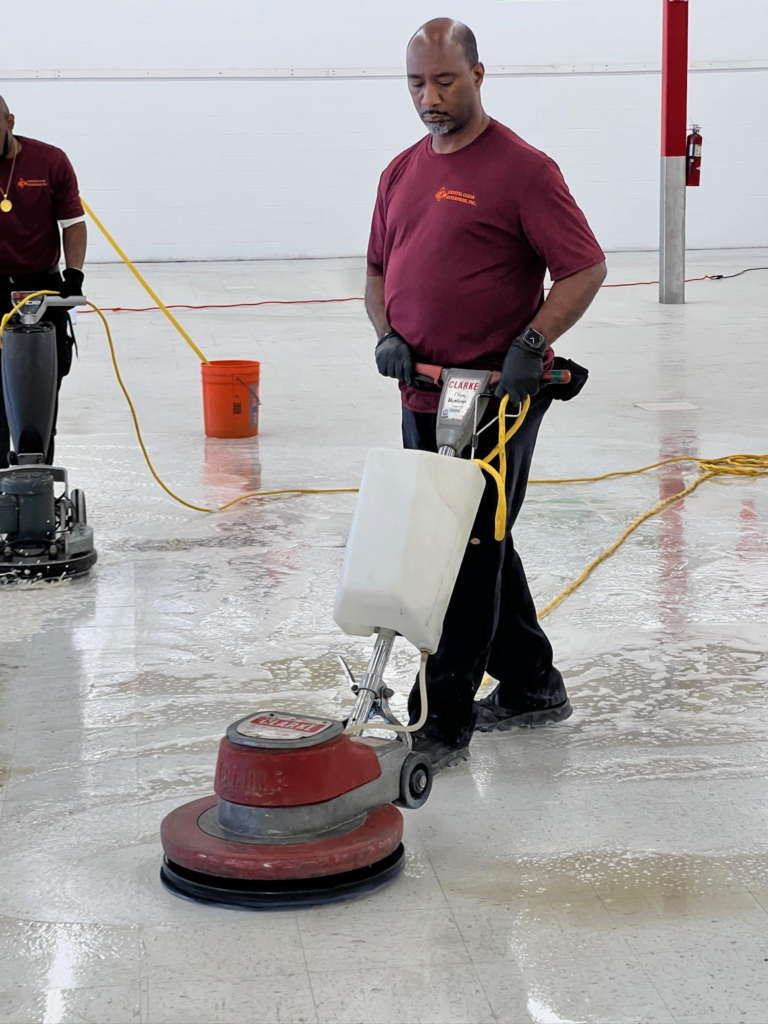 a cleaner using a floor scrubber to make it shine