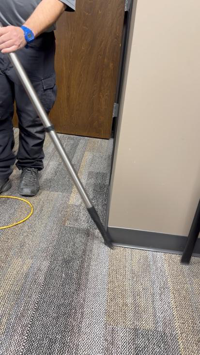 A man using a vacuum cleaner in a commercial office setting