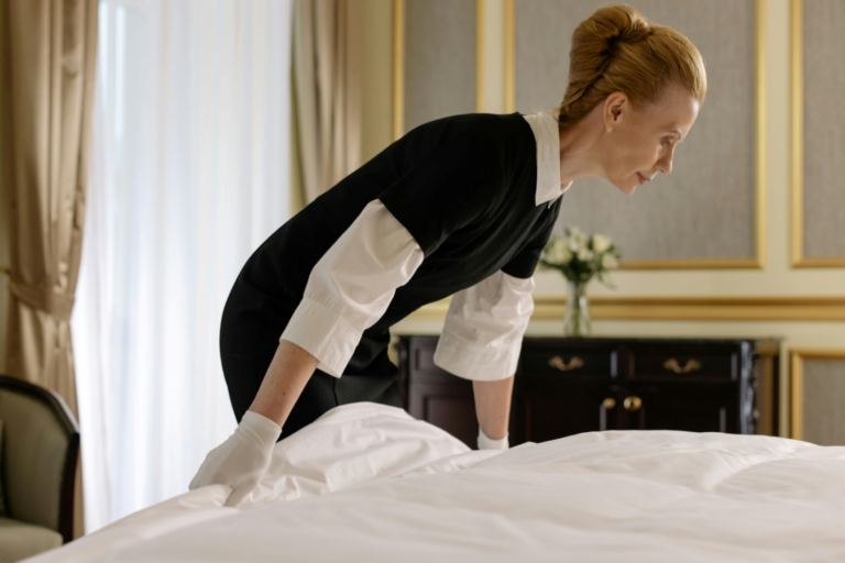 A person making the bed in a guest room