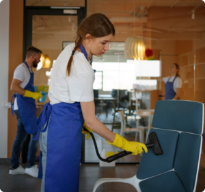 Cleaning technician vacuuming and sanitizing an office chair inside a modern commercial workspace after renovation.
