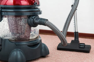 Close-up of vacuum cleaner removing dirt from carpet surface