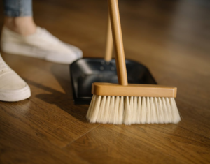 Person sweeping hardwood floor with broom and dustpan